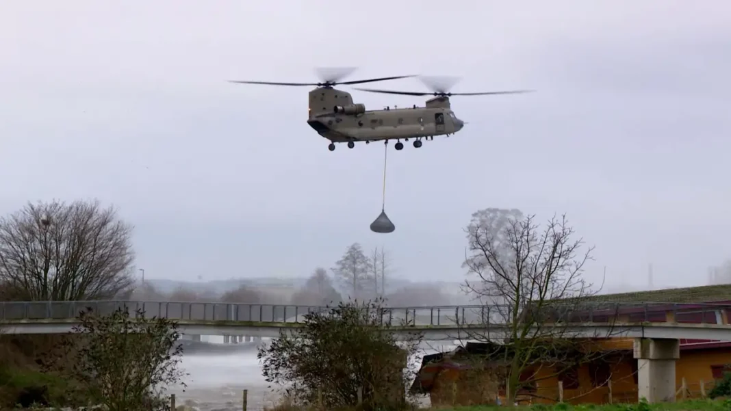 Defense helicopters drop heavy stones on a broken spillway dam near Maastricht